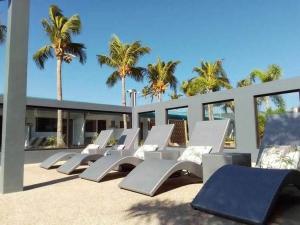 a row of lounge chairs on a patio with palm trees at Cave Beach Resort in Dingalan
