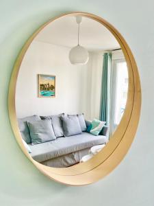 a living room with a couch in front of a mirror at St Nazaire - L'Art Déco - Stationnement Gratuit - Centre ville - Wifi Fibre in Saint-Nazaire