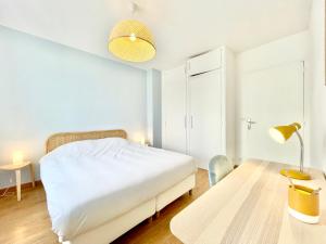 Dormitorio blanco con cama y mesa en St Nazaire - L'Art Déco - Stationnement Gratuit - Centre ville - Wifi Fibre en Saint-Nazaire
