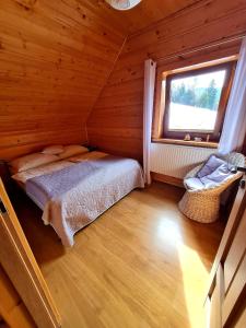 1 dormitorio en una cabaña de madera con cama y ventana en Gorczańska Chata z tarasem widokowym, en Poręba Wielka