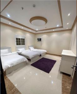 a bedroom with three beds and a rug at H.H apartments شقق مفروشة in Mecca