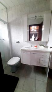 y baño con aseo, lavabo y espejo. en Casa Campos do Jordão, en Campos do Jordão
