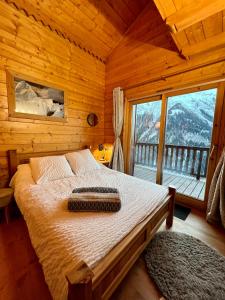 un letto in una camera in legno con una grande finestra di Chalet Rocher a La Thuile Sainte-Foy-Tarentaise