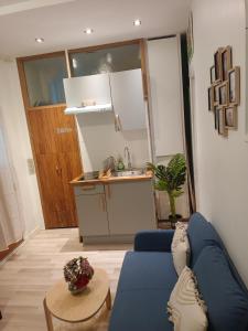 uma sala de estar com um sofá azul e uma cozinha em Home Cosy ARENA Porte de la Chapelle em Paris