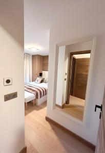 1 dormitorio con espejo y 1 cama en una habitación en Les Chamois D’Arbois, Mont D’Arbois, Megève en Megève