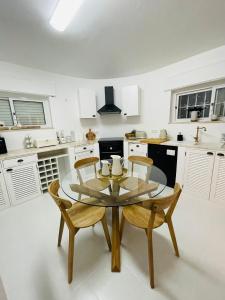 uma cozinha com uma mesa de vidro e 2 cadeiras em Villa Serro das Vinhas em Portimão