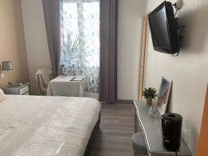 a hotel room with a bed and a television on the wall at Hôtel Restaurant La Plage in Port-Saint-Louis-du-Rhône