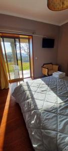 - une chambre avec un grand lit et une porte coulissante en verre dans l'établissement Quinta do Carvalho - Nature Guest Houses, à Guimarães