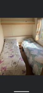 a small room with two beds and a window at 3 bed caravan Norfolk near the coast in Belton