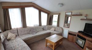 ein Wohnzimmer mit einem Sofa und einem TV in der Unterkunft 3 bed caravan Norfolk near the coast in Belton