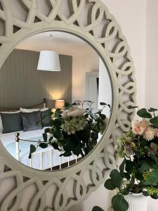 een spiegel die een slaapkamer met een bed en bloemen weerspiegelt bij Wellington Cottage in Ilkley