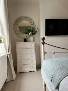 a bedroom with a white dresser and a mirror at Wellington Cottage in Ilkley