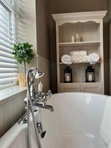 a bathroom with a tub and a shelf with towels at Wellington Cottage in Ilkley