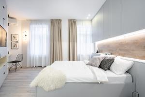 a white bedroom with a large white bed with a furry rug at FOUR Bedroom Apartment, Old Town Bucharest in Bucharest
