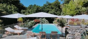 einen Pool mit zwei weißen Sonnenschirmen und Stühlen sowie einem Pool in der Unterkunft Casetta in Ortiporio