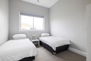 two beds in a white room with a window at Ellenora in Warrnambool