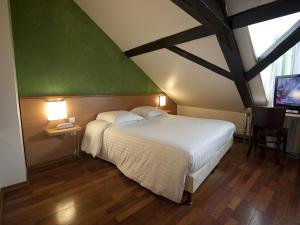 ein Schlafzimmer mit einem weißen Bett und einer grünen Wand in der Unterkunft Hôtel le Grillon in Straßburg