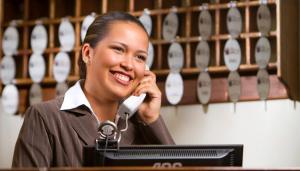a woman talking on a phone in front of a computer at Hostal San Francisco in San Cristóbal