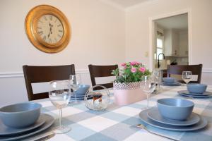 una mesa con platos y gafas y un reloj en la pared en The Promenade Cottage License # 002-2023, en Niagara on the Lake