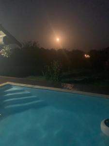 a swimming pool at night with the moon in the background at Popas Regal 