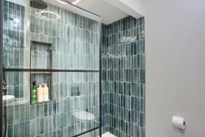 a bathroom with a shower with glass tiles at Urban Oasis Retreat With Luxury Design, Hot Tub, Fire Pit, Breathtaking Downtown & River Views in Pittsburgh +41 photos