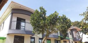 - un bâtiment avec un balcon et un arbre en face dans l'établissement Kinene Residence Motel Entebbe, à Nalugala