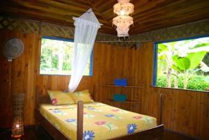 a bedroom with a bed and a window and a chandelier at Casa Amarilla in Puerto Viejo