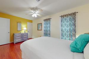 a bedroom with a white bed and a ceiling fan at Birder's Heaven at 621 Palm in Laguna Vista