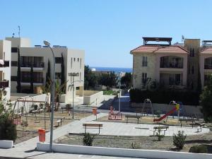 a playground with benches and slides in front of a building at Mazotos Panoramic Village in Mazotos