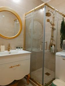 W łazience znajduje się prysznic, umywalka i lustro. w obiekcie PORTO SOFIA w mieście Kumanowo