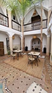a room with tables and chairs and palm trees at Riad Des Arts in Marrakesh