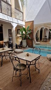 un soggiorno con 2 tavoli e una piscina di Riad Des Arts a Marrakech
