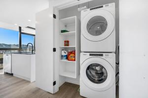 a white laundry room with a washer and dryer at Brand New Luxury Downtown Near the Beach #10 in Kelowna