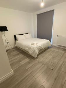 a bedroom with a white bed and a wooden floor at East London - 2 bed Apartment with Parking in Barking