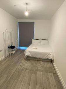 1 dormitorio blanco con 1 cama y suelo de madera en East London - 2 bed Apartment with Parking en Barking