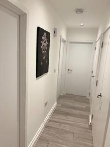 un pasillo con paredes blancas y una pintura en la pared en East London - 2 bed Apartment with Parking en Barking
