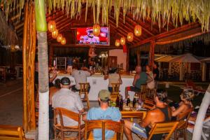 Un gruppo di persone sedute al bar a guardare la TV di HANGA ROA HOTEL a Montañita