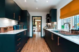 a kitchen with dark blue cabinets and wooden floors at Luxury Renovated Bungalow with wheel chair access, Hot Tub and Fire Pit 