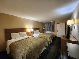 a hotel room with two beds and a flat screen tv at Budget Host Inn in Henderson