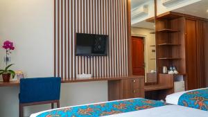 Zimmer mit 2 Betten und einem TV an der Wand in der Unterkunft Lombok Vaganza Hotel in Mataram