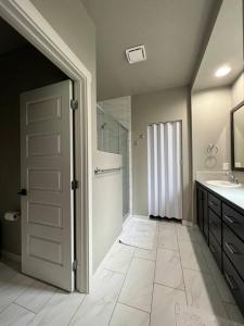 ein Bad mit einer Dusche, einem Waschbecken und einer Tür in der Unterkunft Great Location! Modern 3 BR - Wifi - Netflix in Meridian