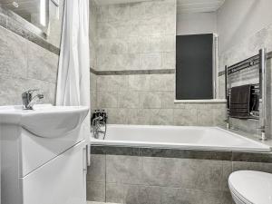 a bathroom with a tub and a sink and a toilet at 3 bed home in Tonypandy with Balcony View Room in Llwyn-y-pia