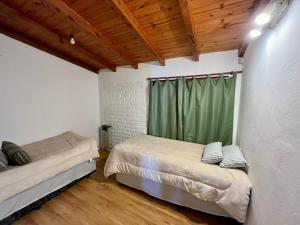1 dormitorio con 2 camas y cortina verde en Casa en Bariloche con salida al lago en San Carlos de Bariloche