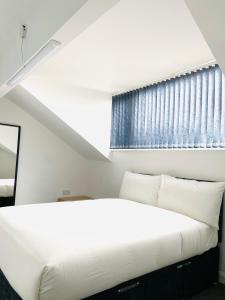 a white bed in a room with a window at Beautiful 4 Bedroom 2 bathroom House close to city centre in Leeds