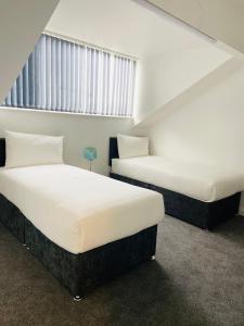 two twin beds in a room with a window at Beautiful 4 Bedroom 2 bathroom House close to city centre in Leeds