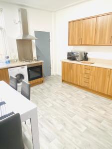 a large kitchen with wooden cabinets and a stove at Beautiful 4 Bedroom 2 bathroom House close to city centre in Leeds