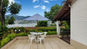 a patio with a table and chairs and an umbrella at Casa da Baía in Angra dos Reis