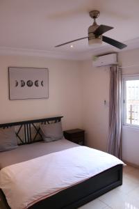 1 dormitorio con 1 cama y ventilador de techo en The Rink Apartment's, en Sukuta