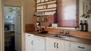 een keuken met witte kasten, een wastafel en een raam bij Rush Cottage in Havelock North