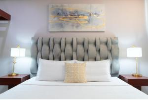a bedroom with a white bed with two lamps at Victoria City Hotel in Oranjestad